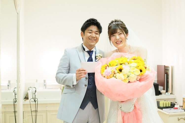 結婚式直前の控え室で花束と手紙をもらった新郎新婦並んで記念撮影